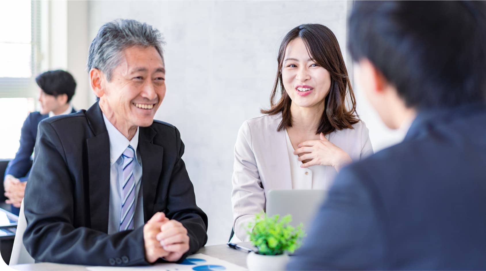 スーツ姿で話し合う３人の人物