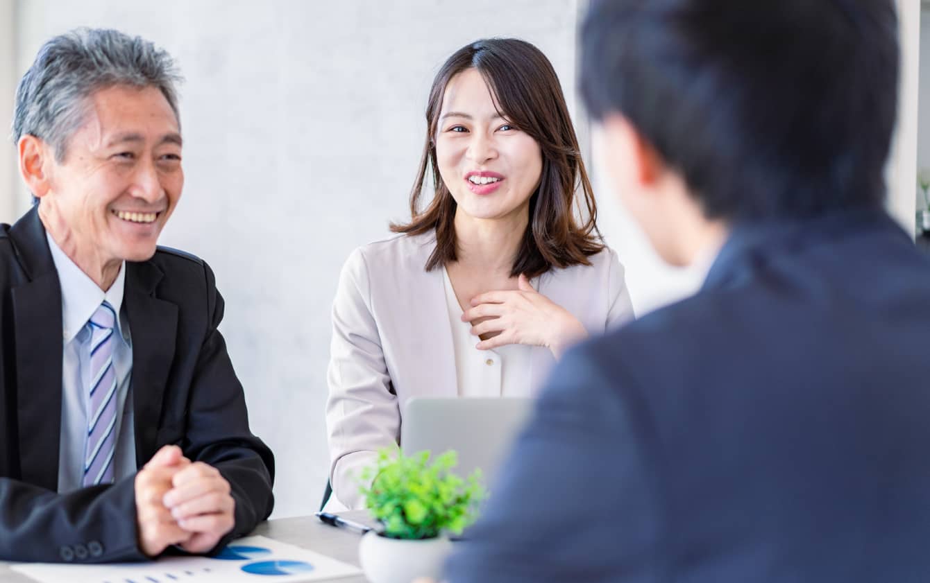 スーツ姿で話し合う３人の人物